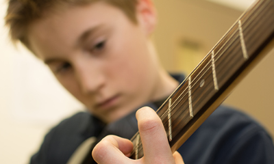 Close up of a young student playing the guitar