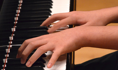 Close up of a young student's hands at the piano
