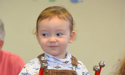 A toddler smiles holding music makers
