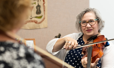 A faculty member teaches violin to an older adult student