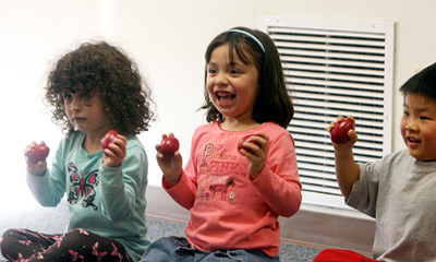 Three early childhood students enjoying exploring rhythms with egg shakers