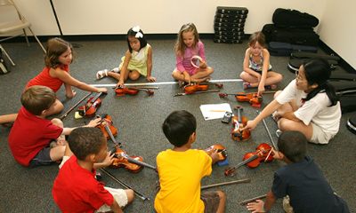 Young students in a circle learning violin