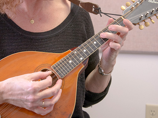 Close up of an adult playing a mandolin