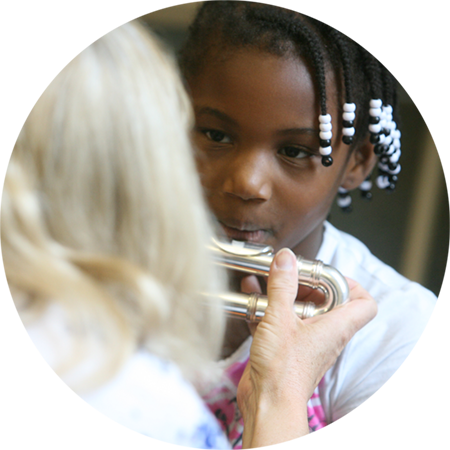 A faculty member helps a young student play the flute