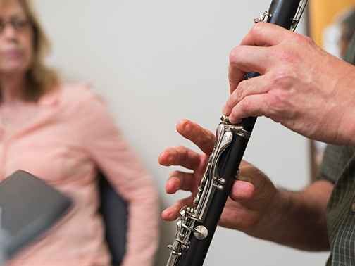 A faculty member watches an adult student play the clarinet