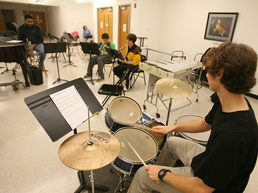 Students performing on drums, guitar, trumpet