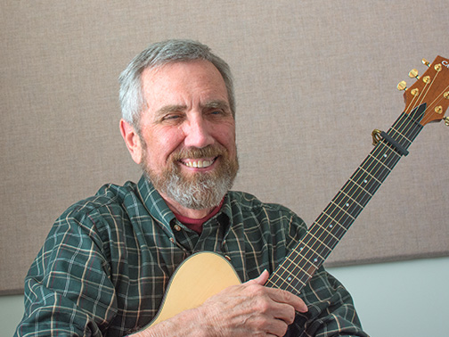 An older student smiling with a guitar