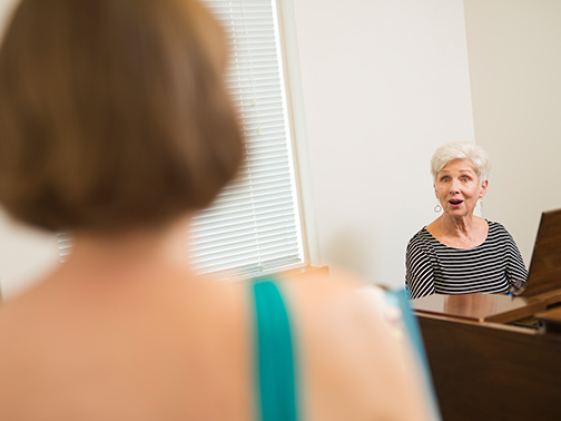 A faculty member leads a student in a voice lesson